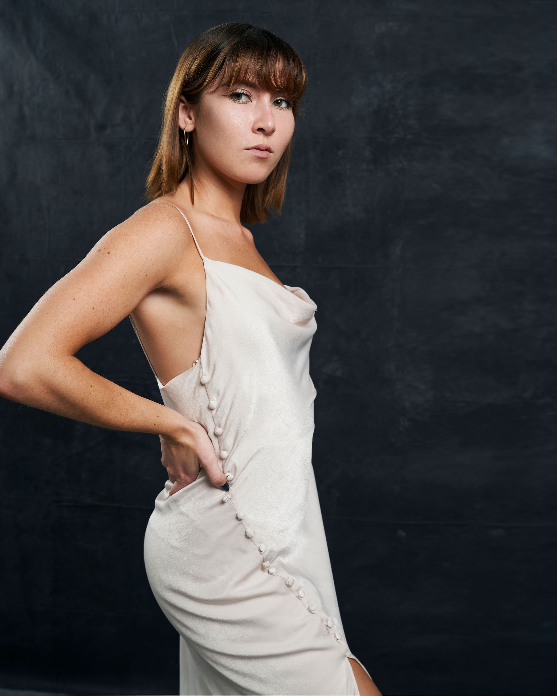 A woman in a white dress is standing in front of a black background