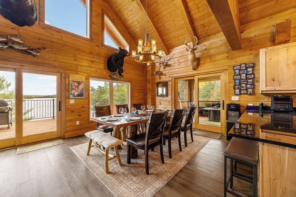 Rustic dining room with a long table, bear and deer mounts, and large windows.
