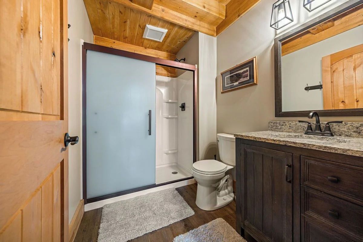 Bathroom with a frosted glass shower door, wooden vanity, and toilet.