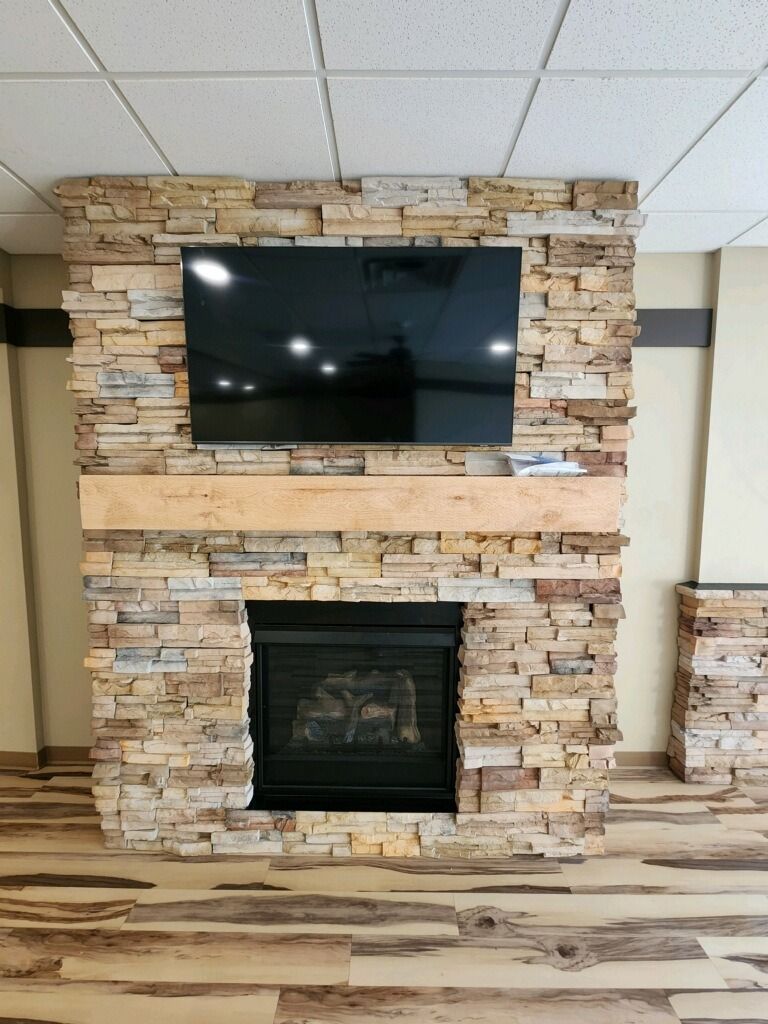 Fireplace with stone facade, TV mounted above. Wooden mantel, wooden floors.
