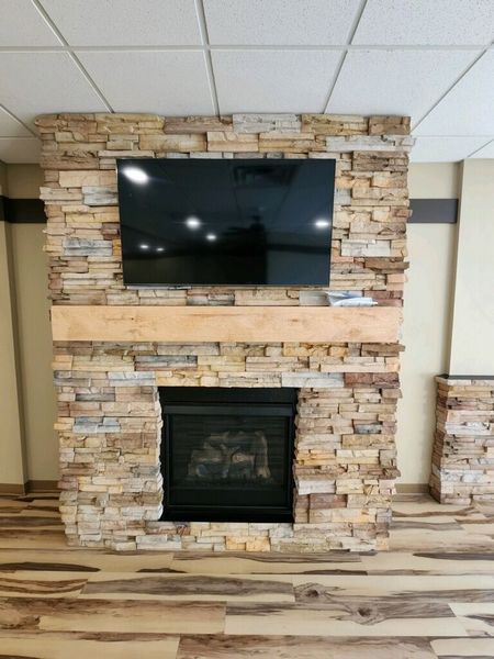 Fireplace with stone facade, TV mounted above. Wooden mantel, wooden floors.