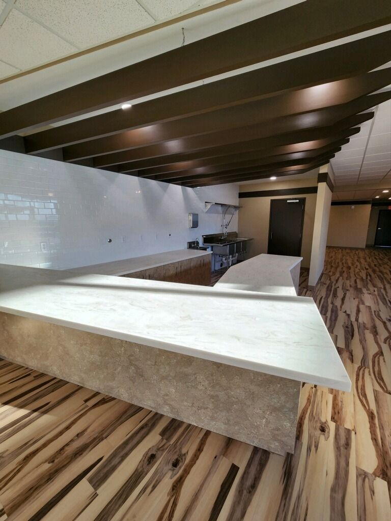 Modern bar area with light-colored counter, wooden ceiling beams, and patterned flooring.