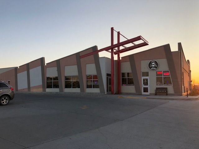 A commercial building with an angled facade and red cross-shaped structure at the entrance.