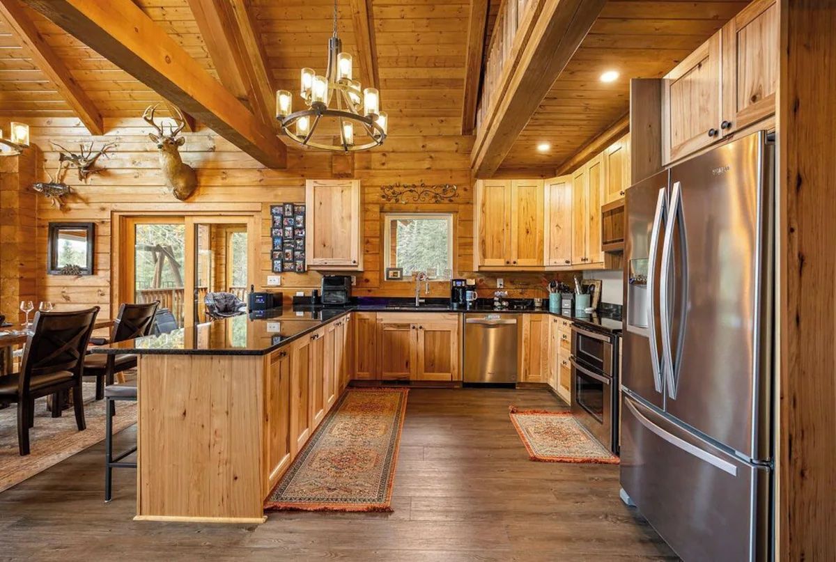 Wooden kitchen with stainless steel appliances, granite countertops, and rustic decor.