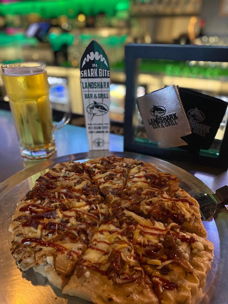 Pizza on a table with a glass of beer, menu stand, and napkins in a restaurant setting