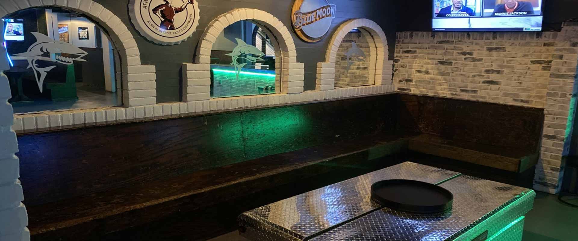 Stone bar counter with three arched windows, dark bench seating, and a TV in a cozy restaurant interior
