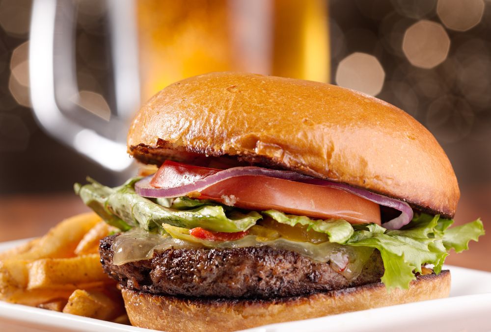 Close-up of a cheeseburger with lettuce, tomato, and fries on a plate