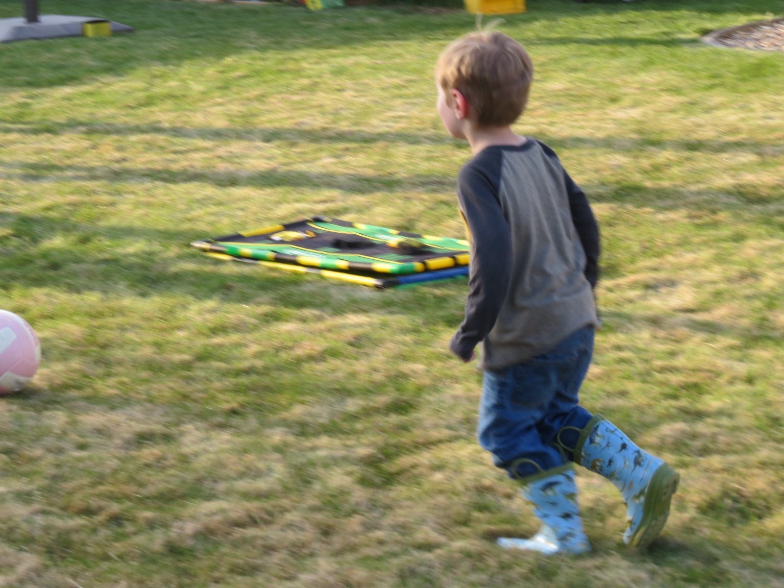 A young boy is playing with a soccer ball in the grass