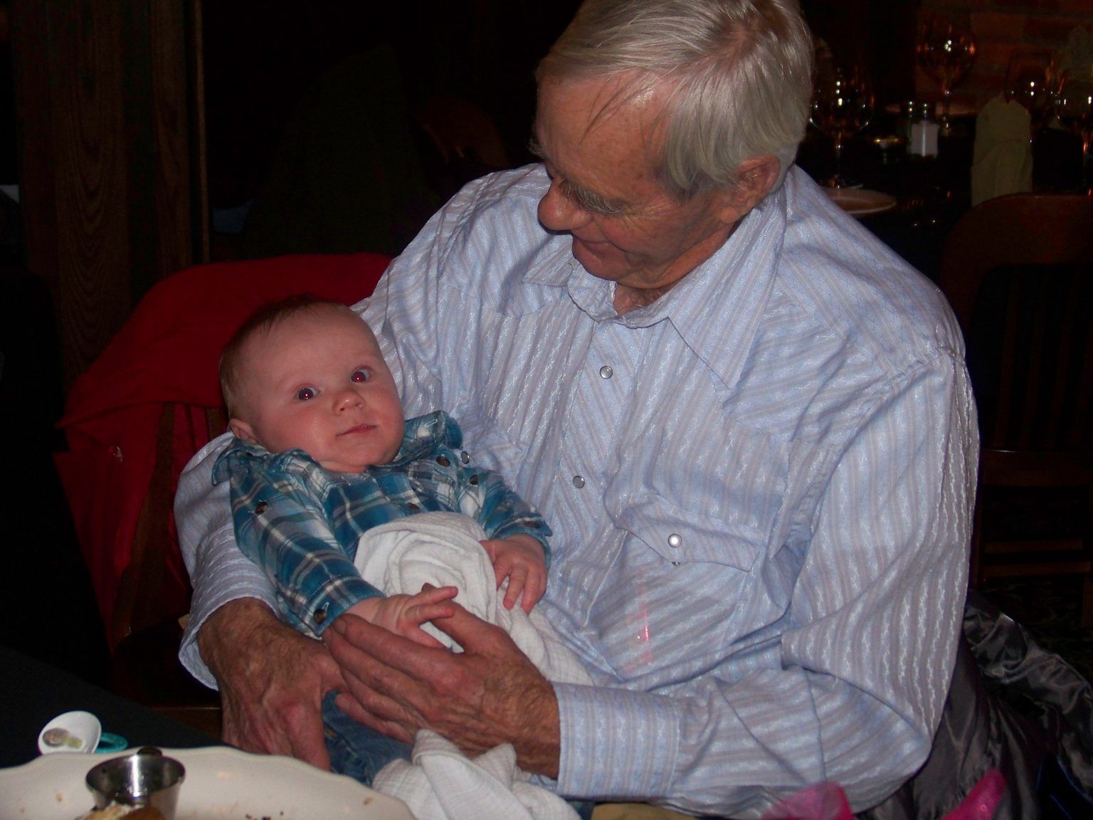 An older man is holding a baby in his arms