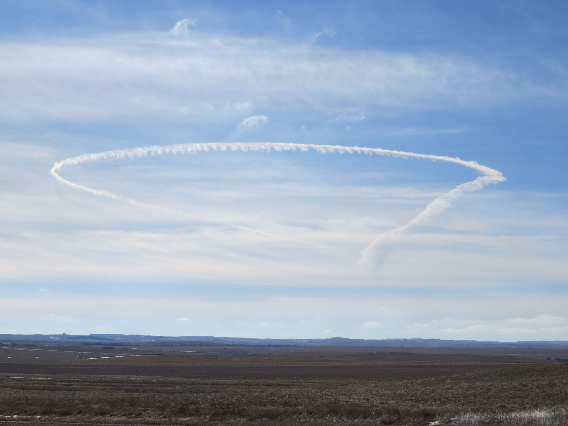 A circle of clouds in the sky over a desert.