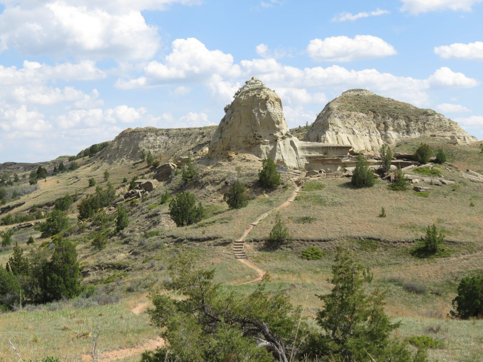 A large rock formation in the middle of a grassy field