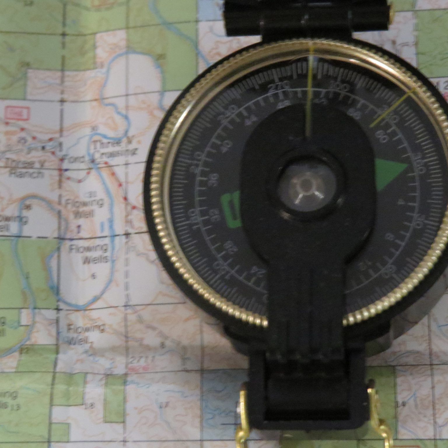 A compass is sitting on top of a map that says fishing wells