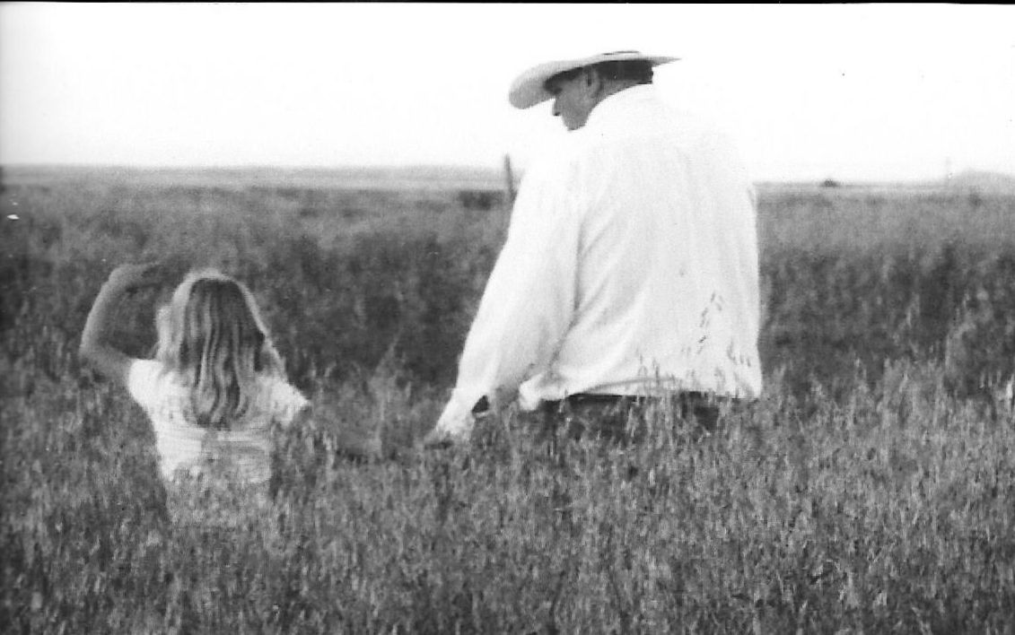 A black and white photo of a man and two girls in a field.