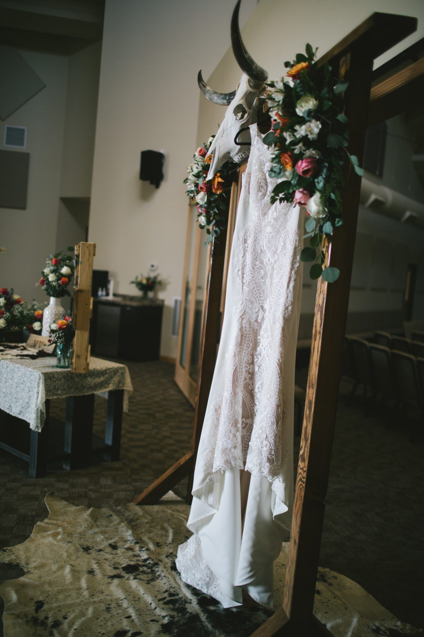 A wedding dress is hanging on a wooden arch in a church.