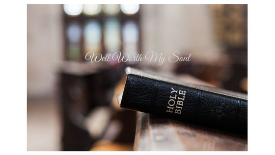 A holy bible is sitting on top of a wooden table.
