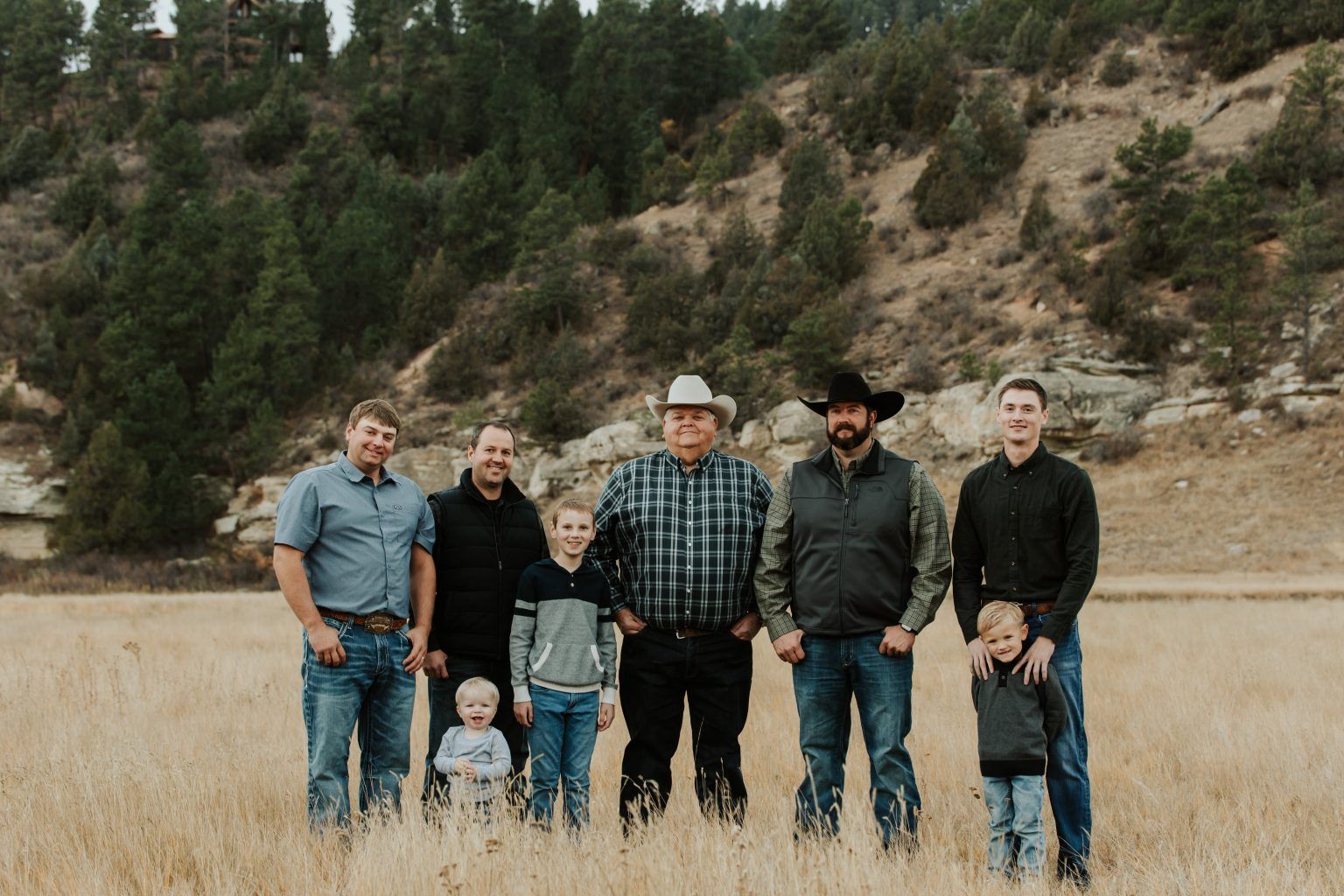 A group of men and children are standing in a field.