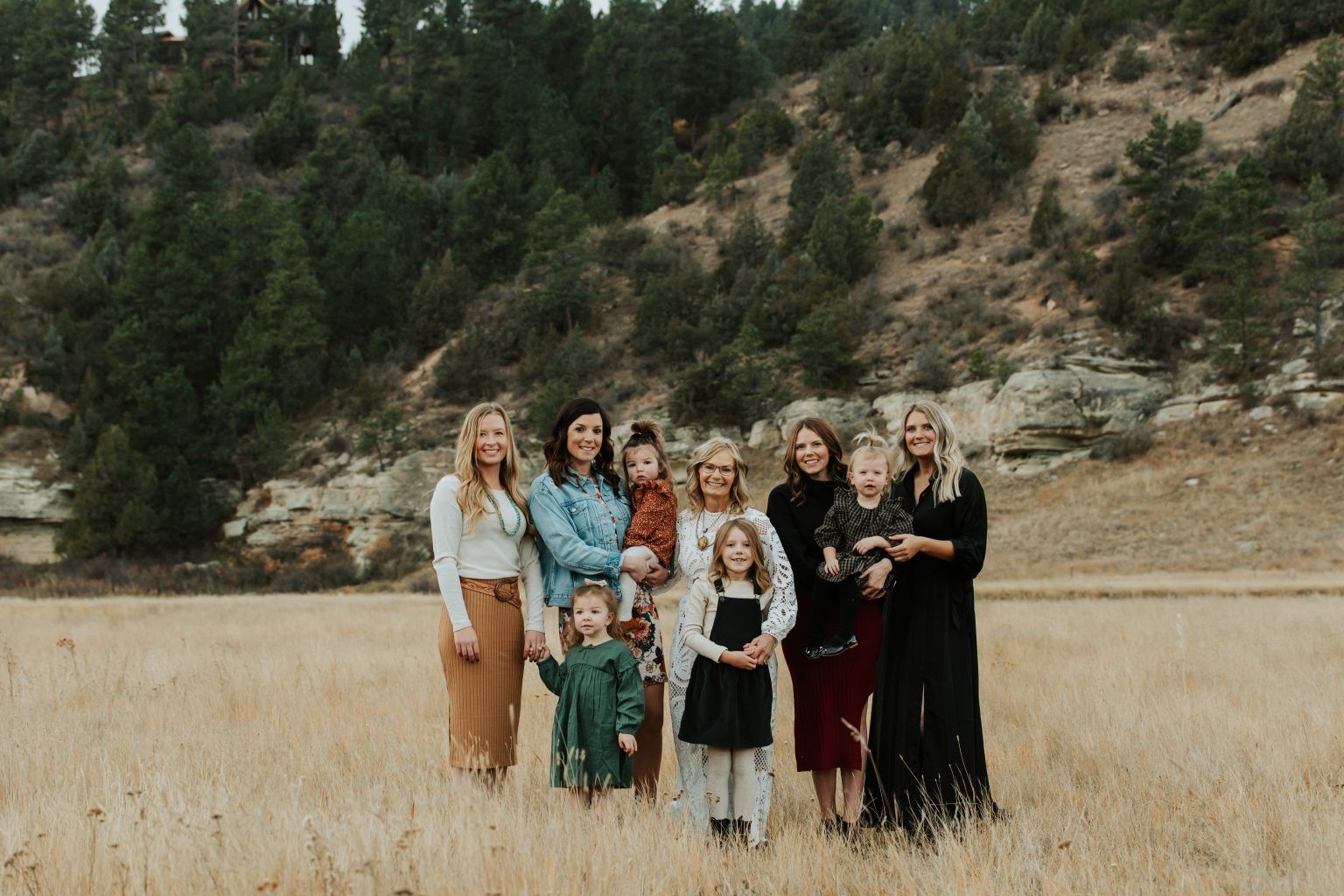 A group of women and children are standing in a field.