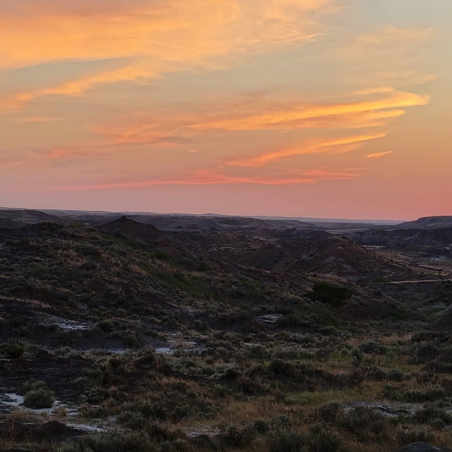 A sunset over a desert landscape with mountains in the background.