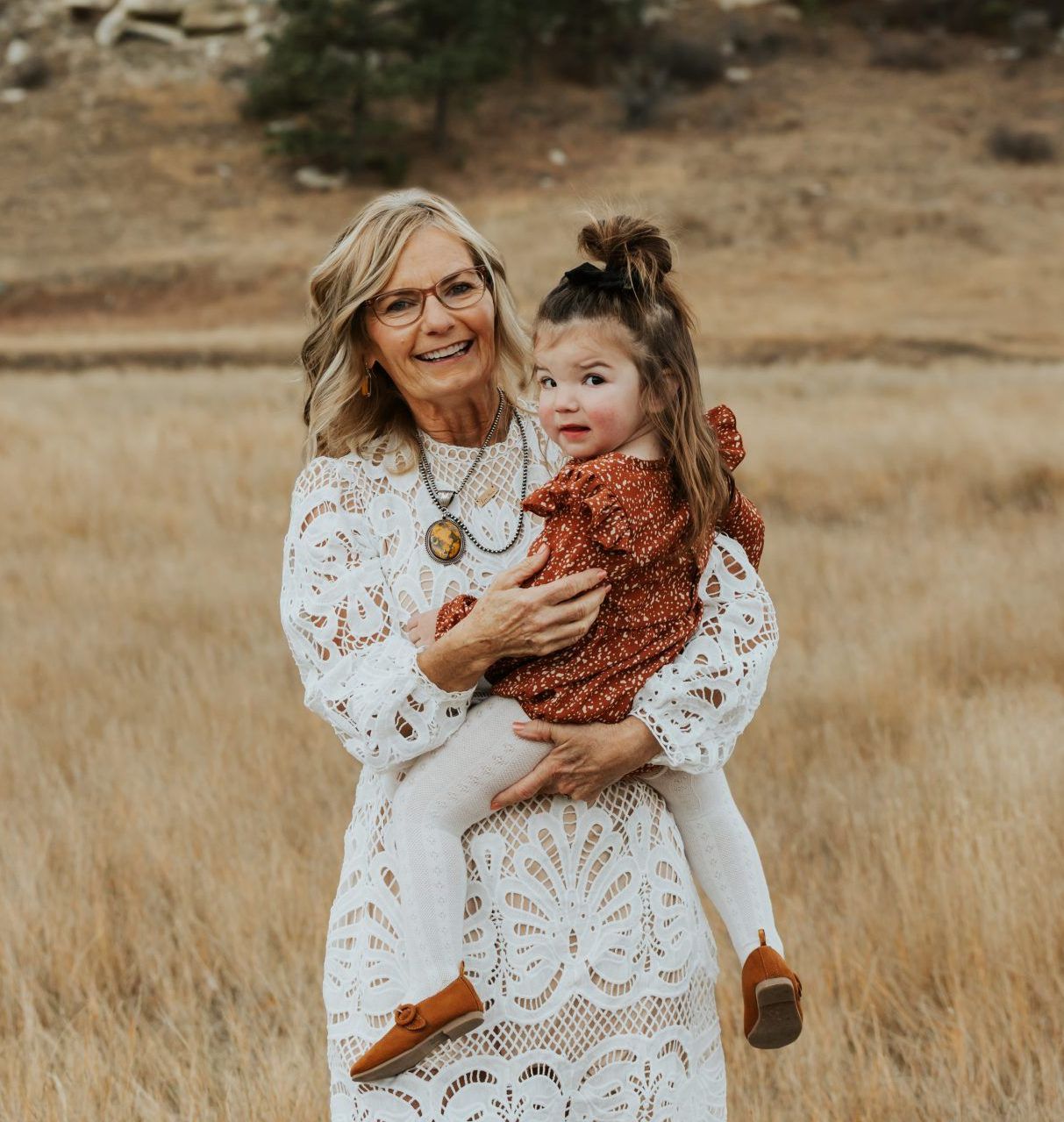 A woman is holding a little girl in her arms in a field.