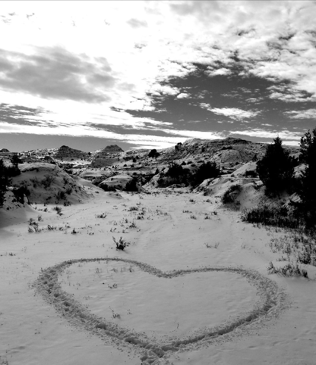 A black and white photo of a heart drawn in the snow