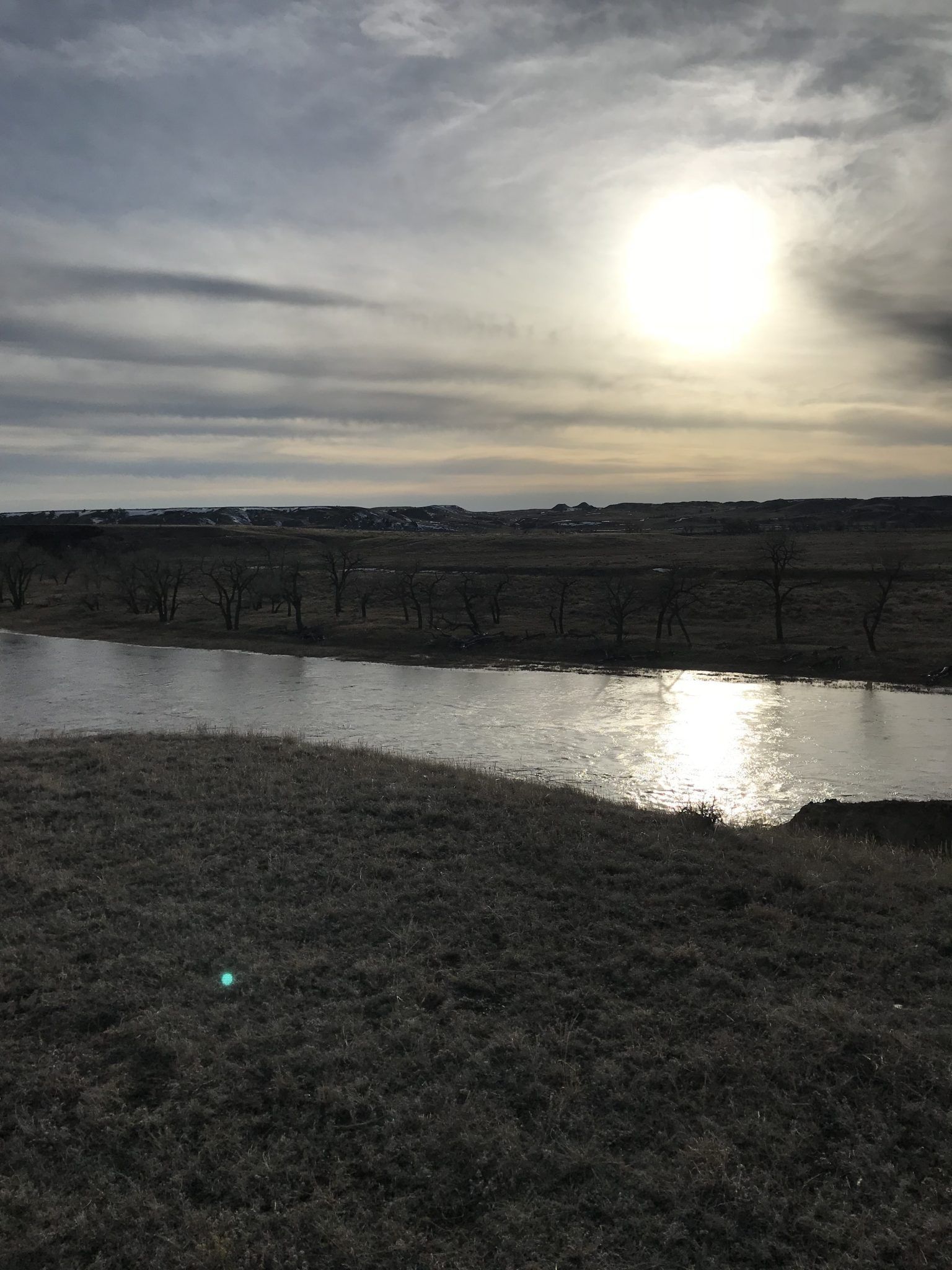 The sun is shining through the clouds over a body of water