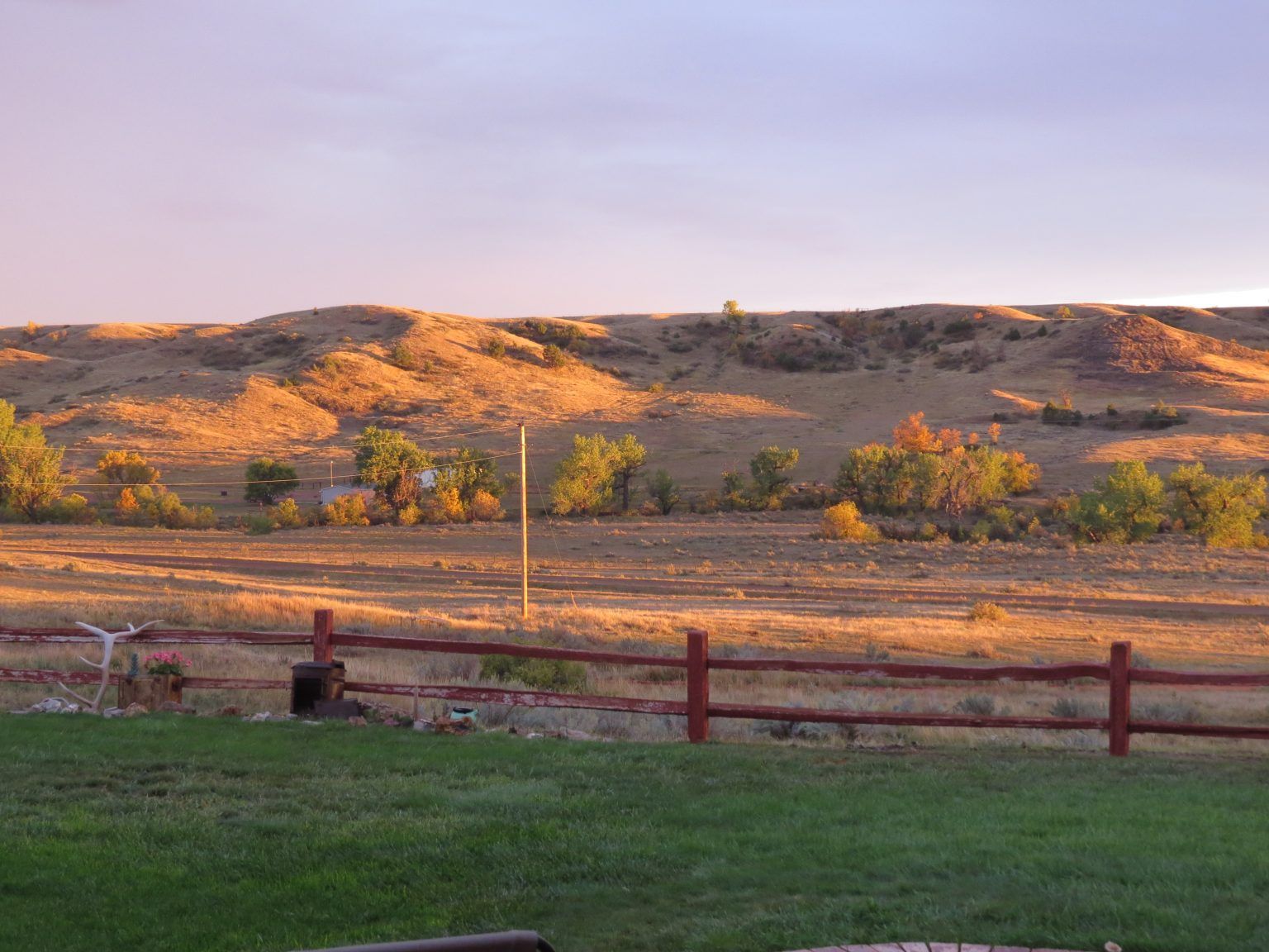 A red fence surrounds a grassy field with mountains in the background.