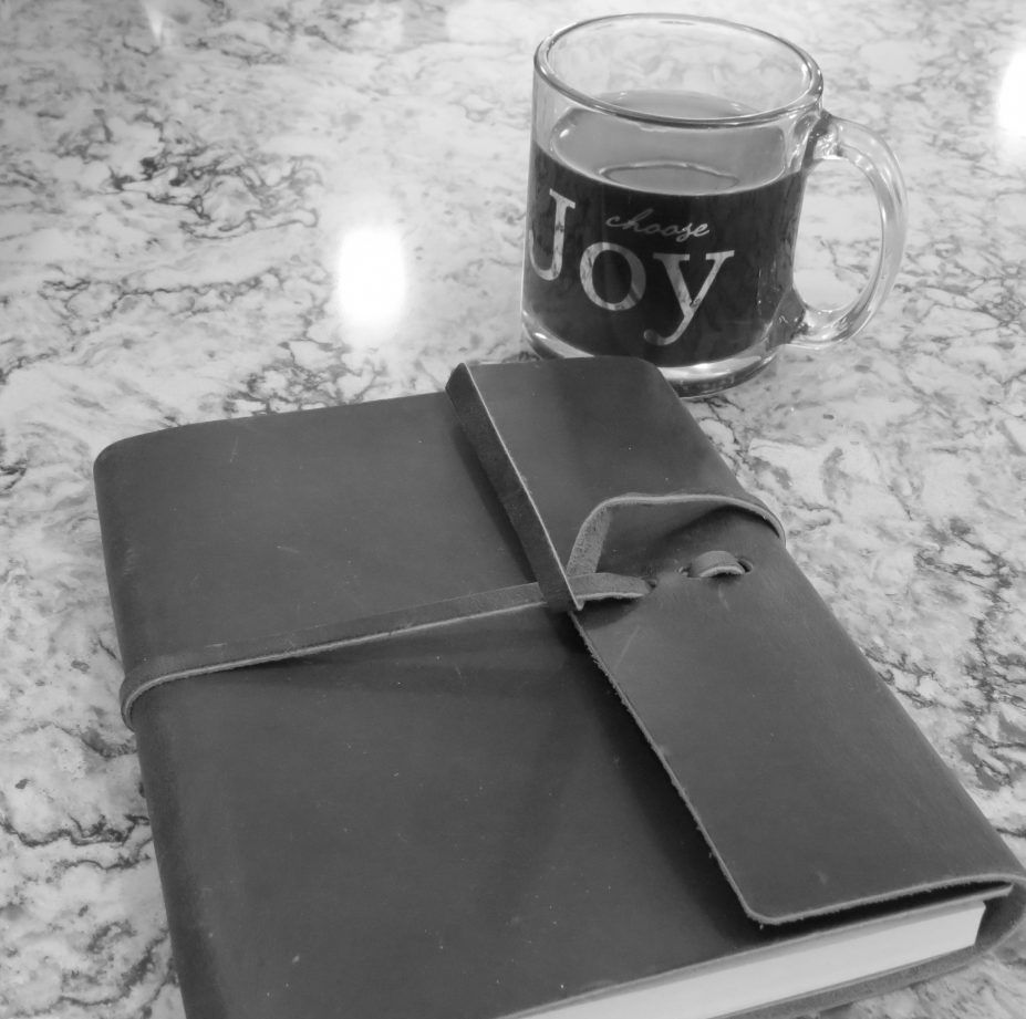 A black and white photo of a book and a mug that says joy