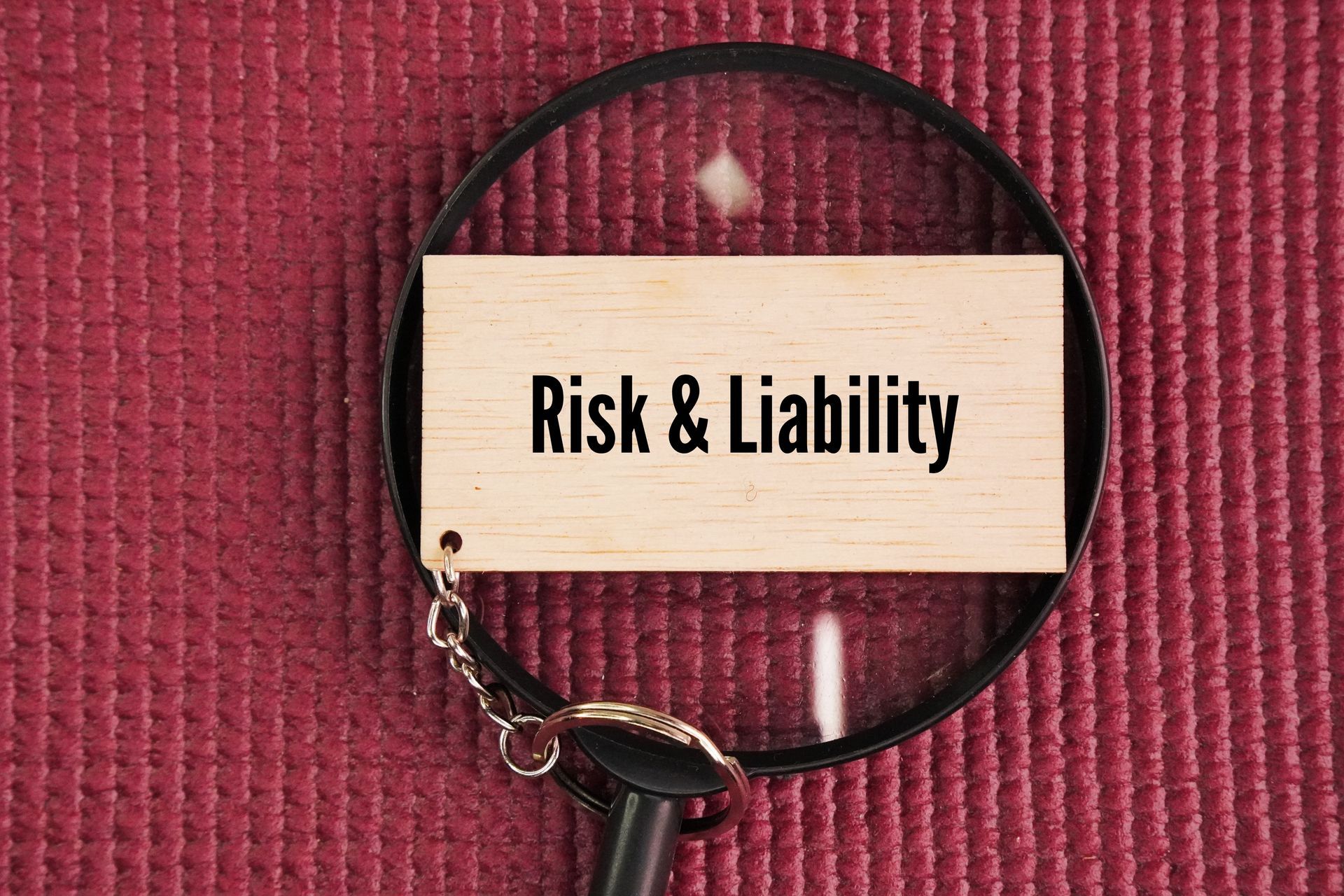 Magnifying glass highlighting risk and liability sign for business liability coverage concept.