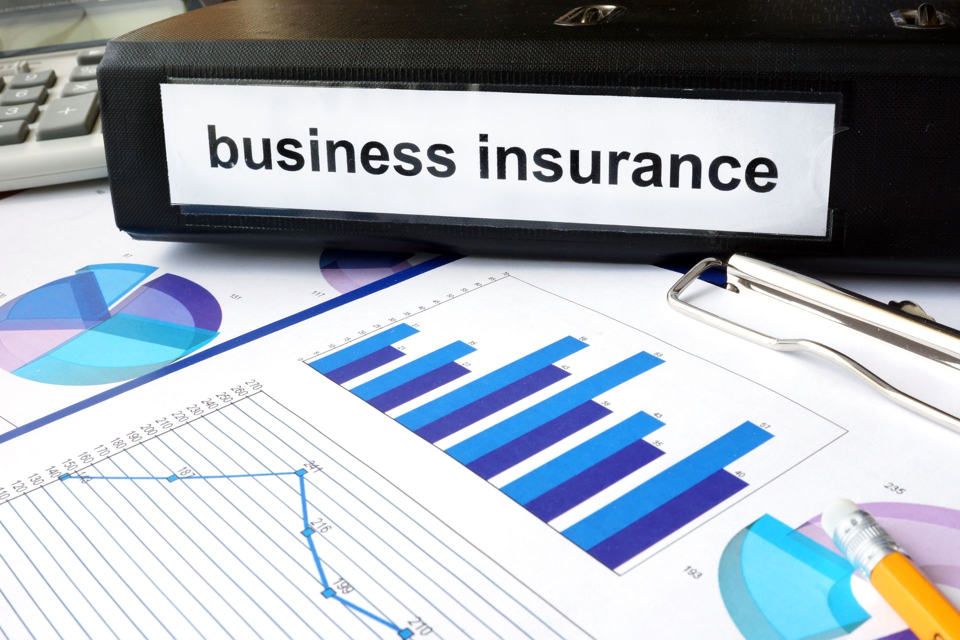 Business insurance binder with charts and graphs on a desk.