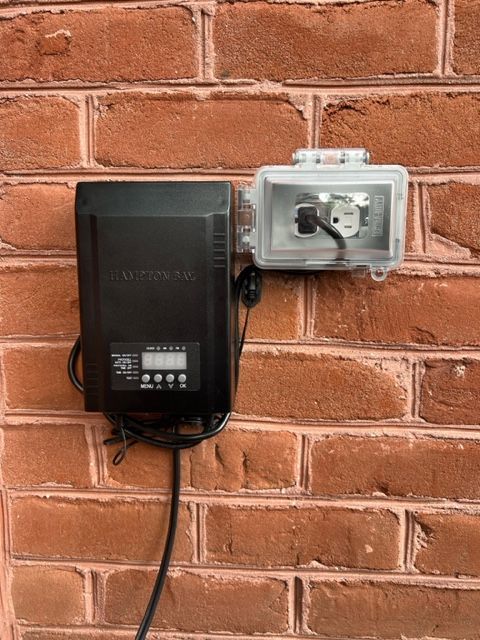 A black box is attached to a brick wall.