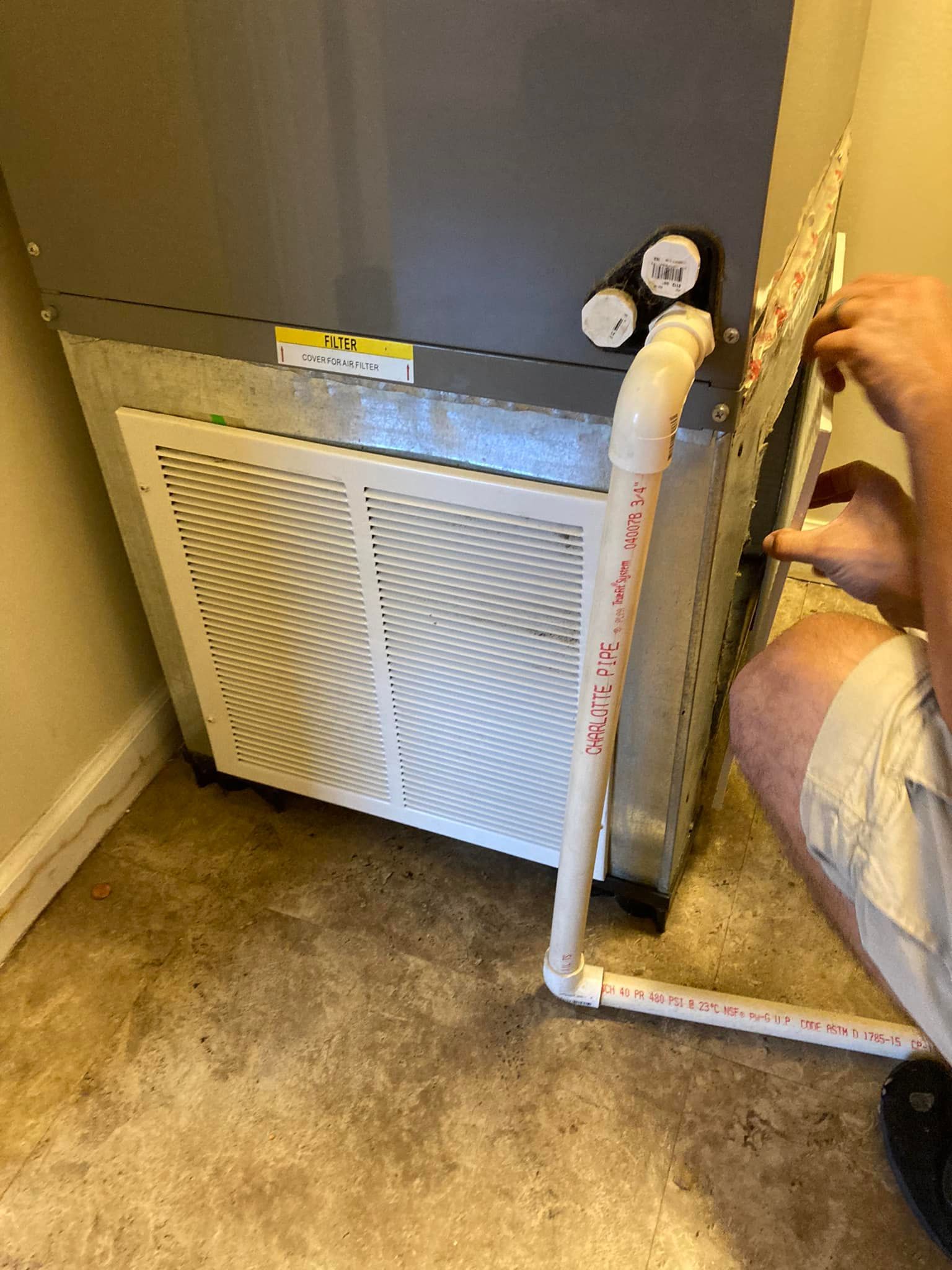 A man is working on an air conditioner in a room.