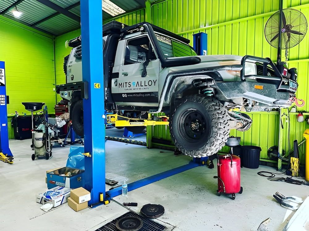 Gray Off-road Truck on a Lift in a Garage. Green Walls, Tools, and a Fan — Nova Auto Innovations in Swansea, NSW