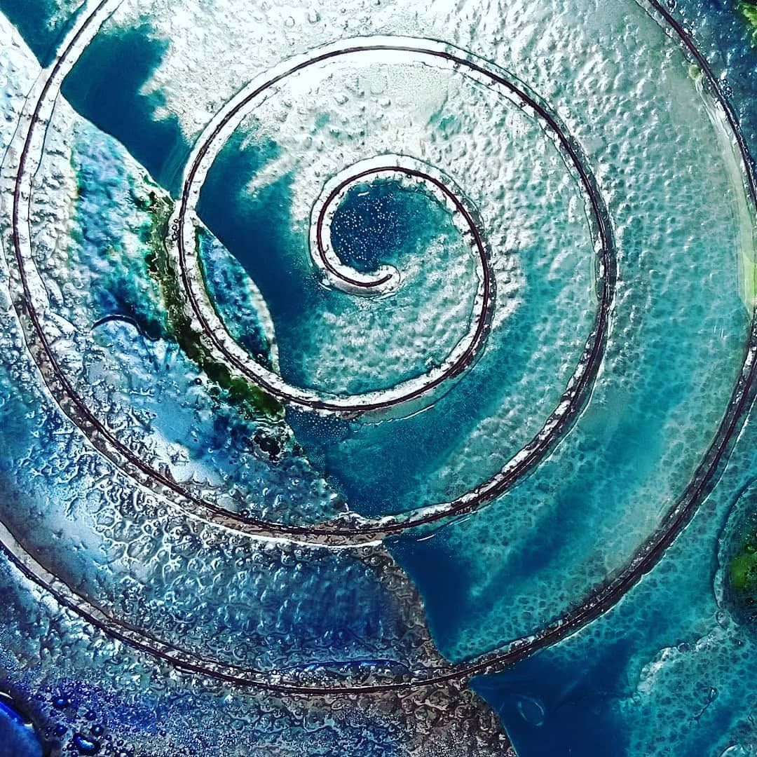 Espiral de vidrio azul con remolinos concéntricos y superficie texturizada.