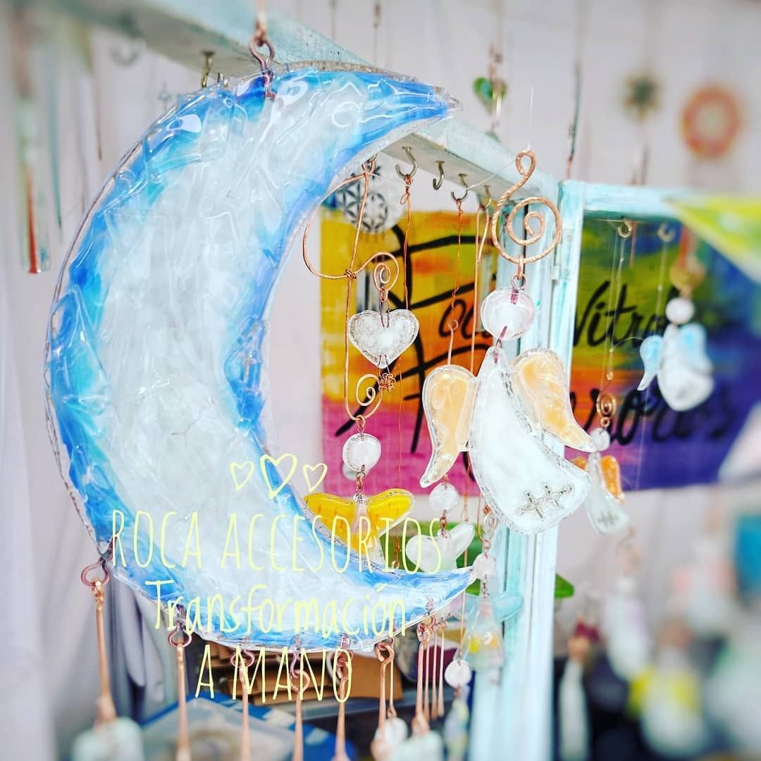 Luna creciente azul y atrapasueños rosa colgando en una colorida composición decorativa.