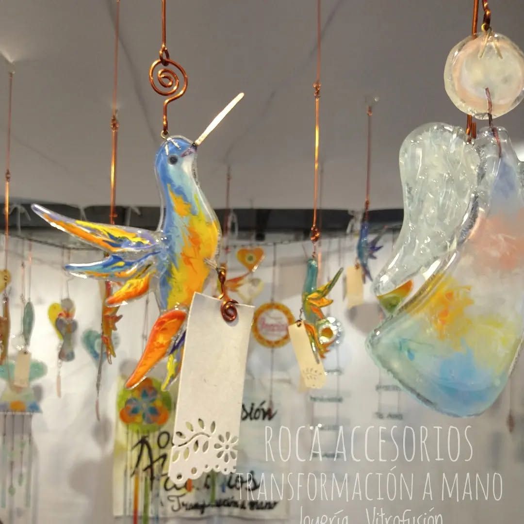 Adornos de pájaros y ángeles de cristal de colores colgando en el escaparate de una tienda.