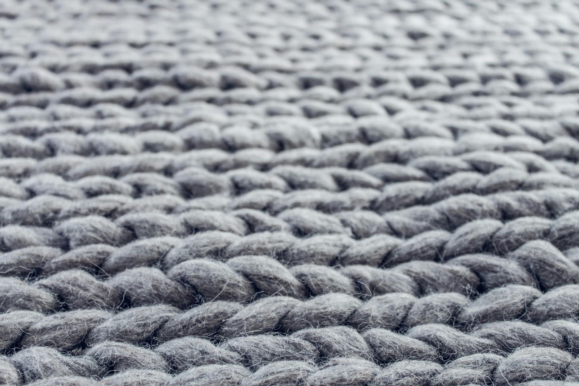 Close-up of gray, chunky knit fabric with textured, braided appearance.