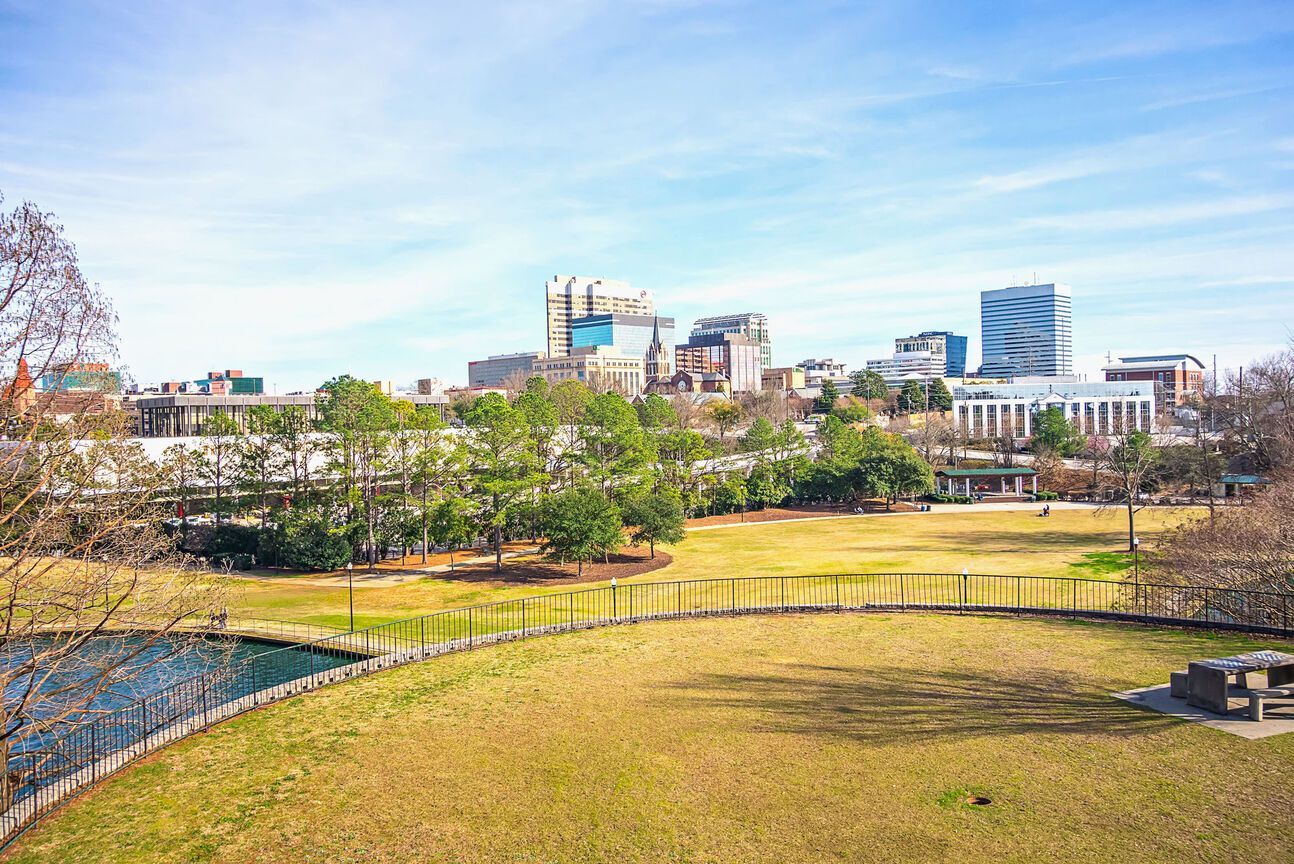 Scenic view of Columbia, South Carolina's skyline with a park in the foreground, blue sky overhead.