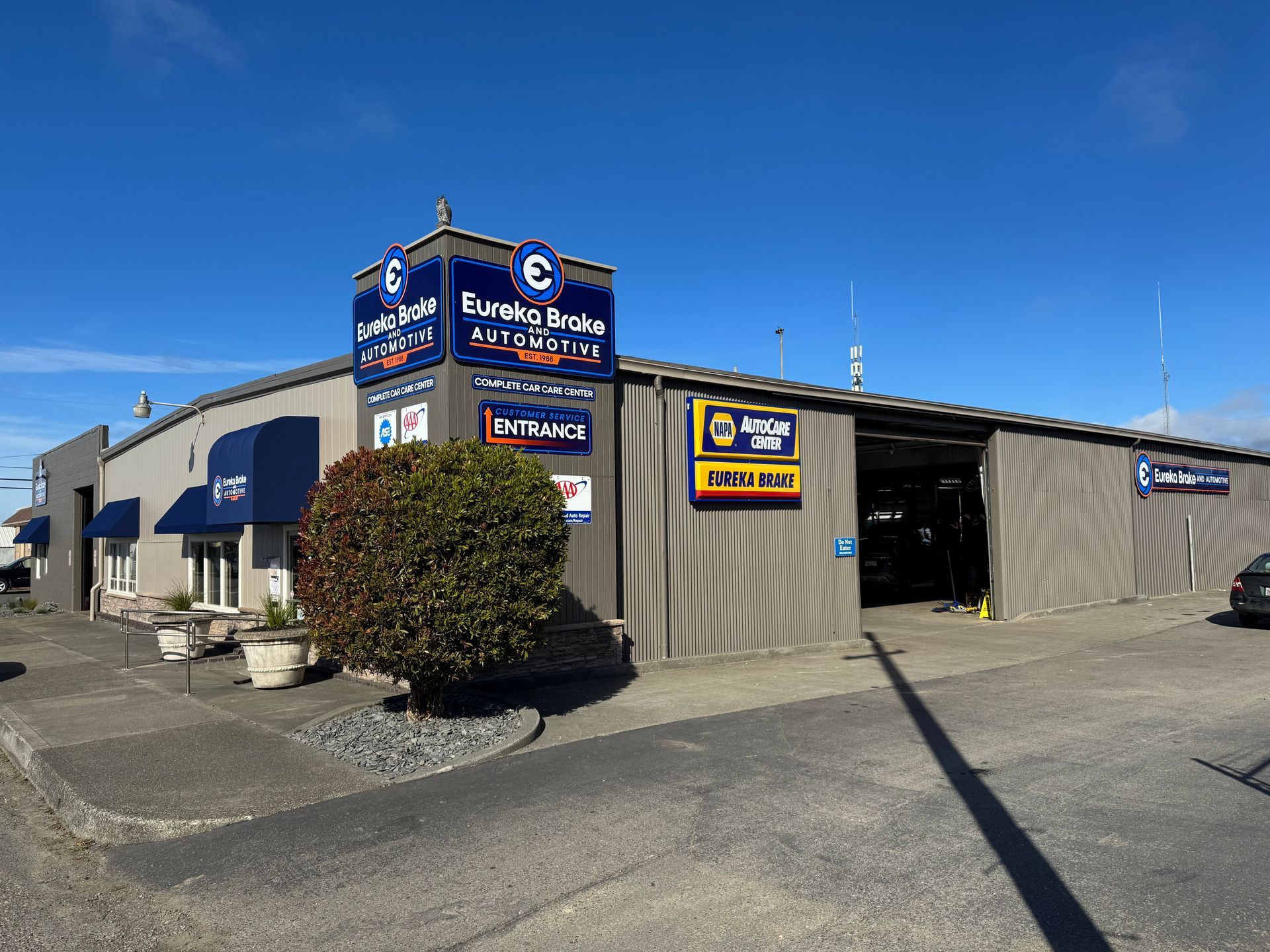 A tan automotive repair building with blue signage for