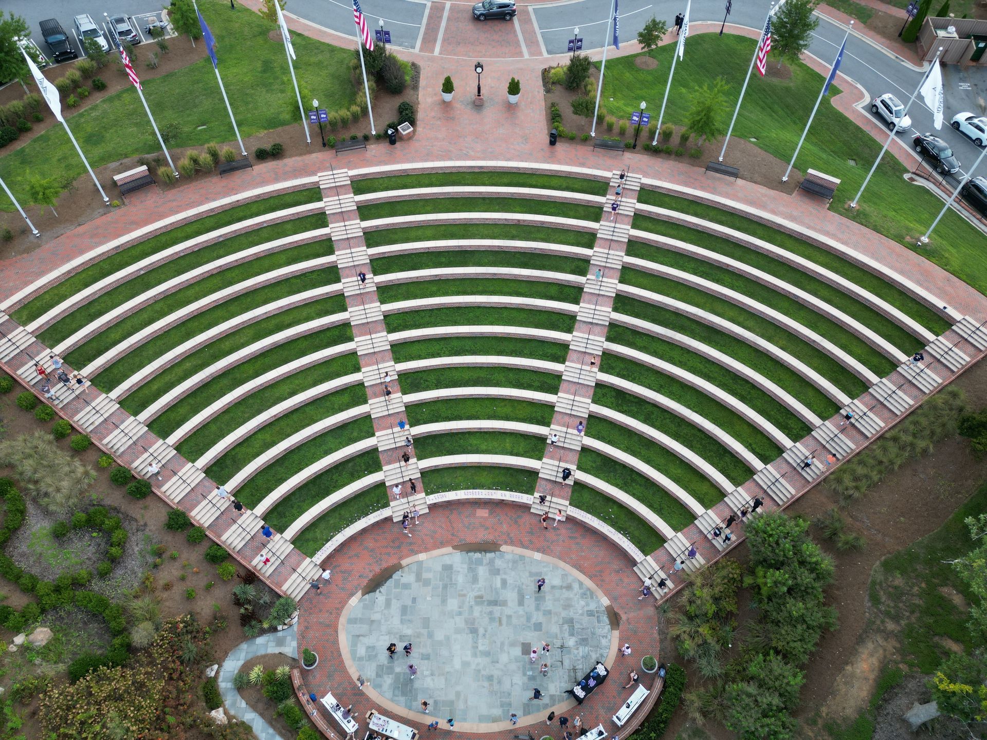 Outdoor amphitheater with tiered seating, stage, and surrounding greenery.