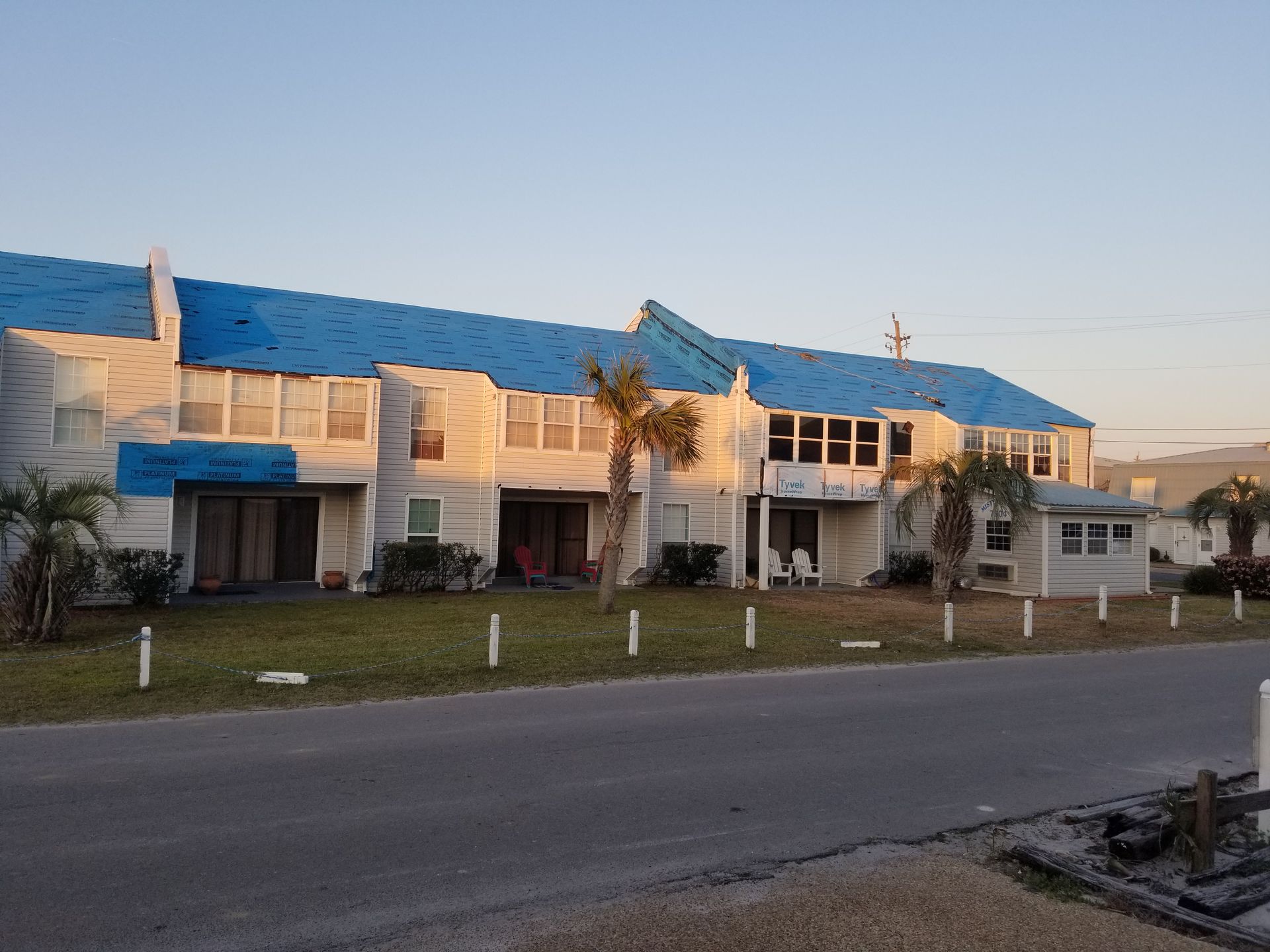 A white building with a blue roof and palm trees