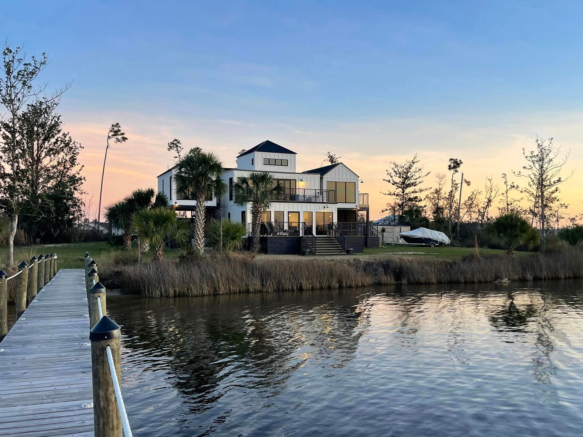 A large house is sitting on a small island in the middle of a body of water.