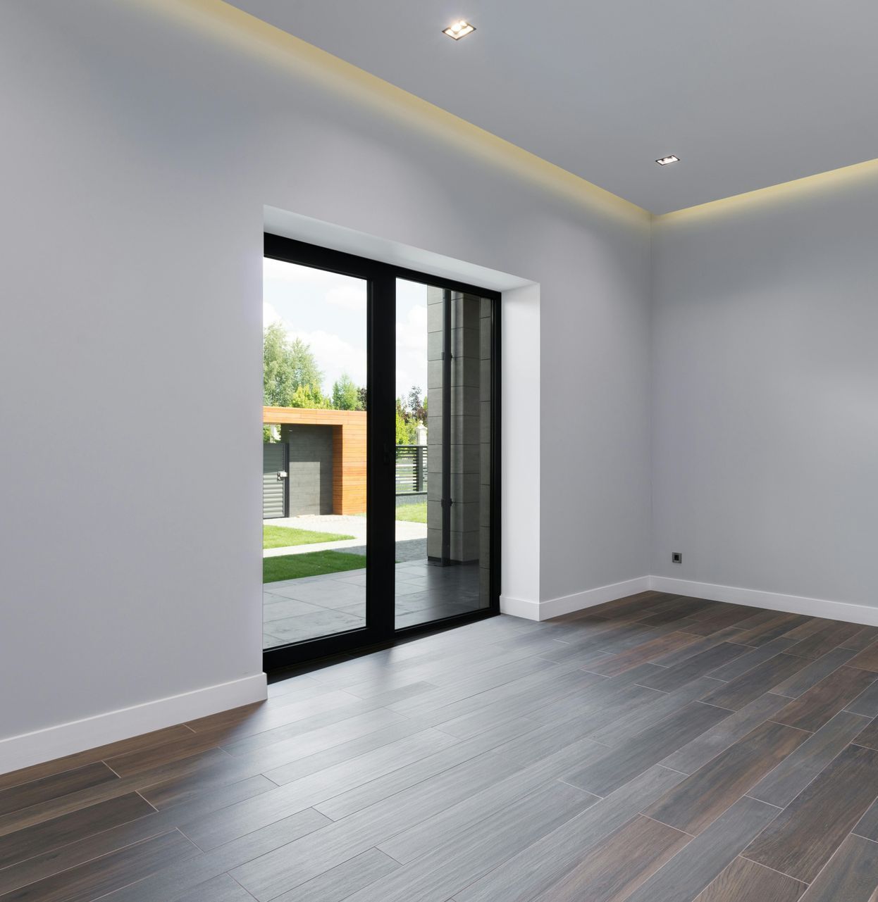 An empty room with hardwood floors and a sliding glass door