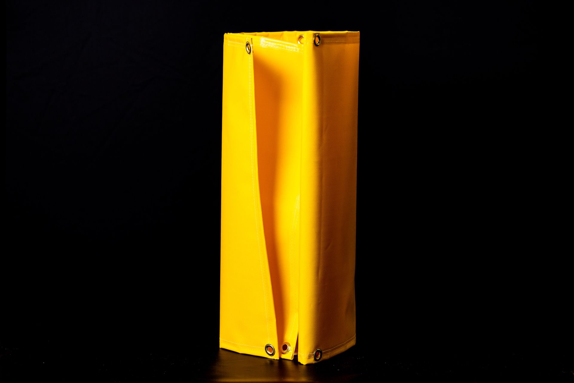 Yellow folded paper bag standing upright on a black background