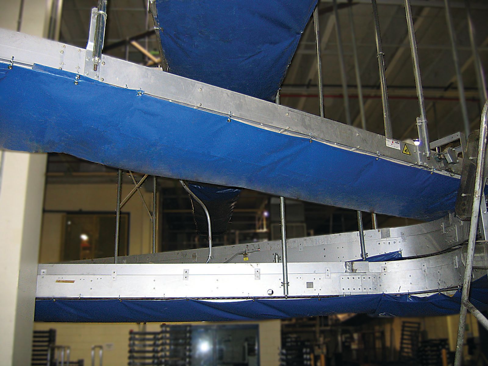 Blue and white aircraft fuselage section inside an industrial hangar or workshop