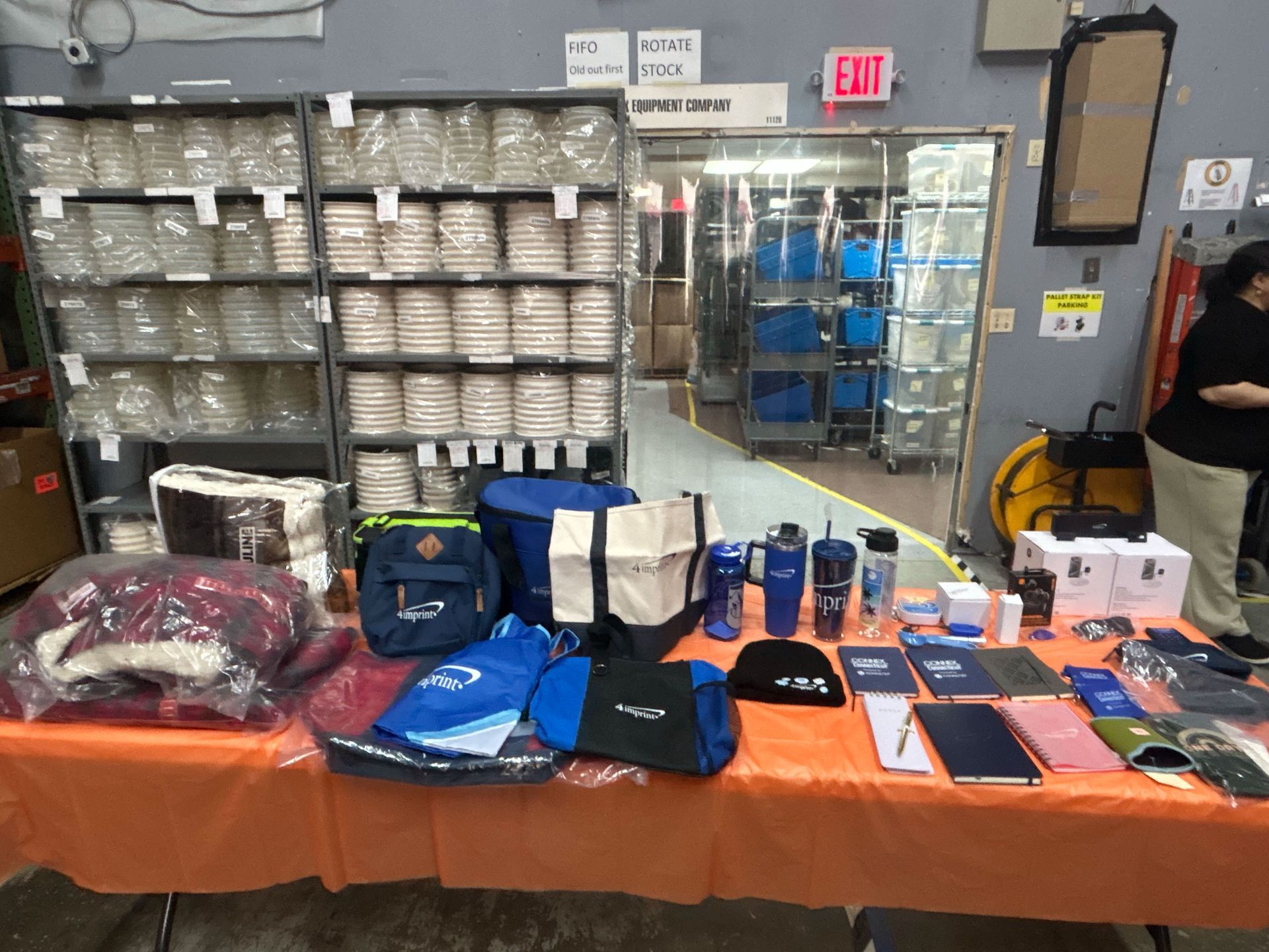 Table of assorted merchandise display in a store, with shelves of stacked goods behind it