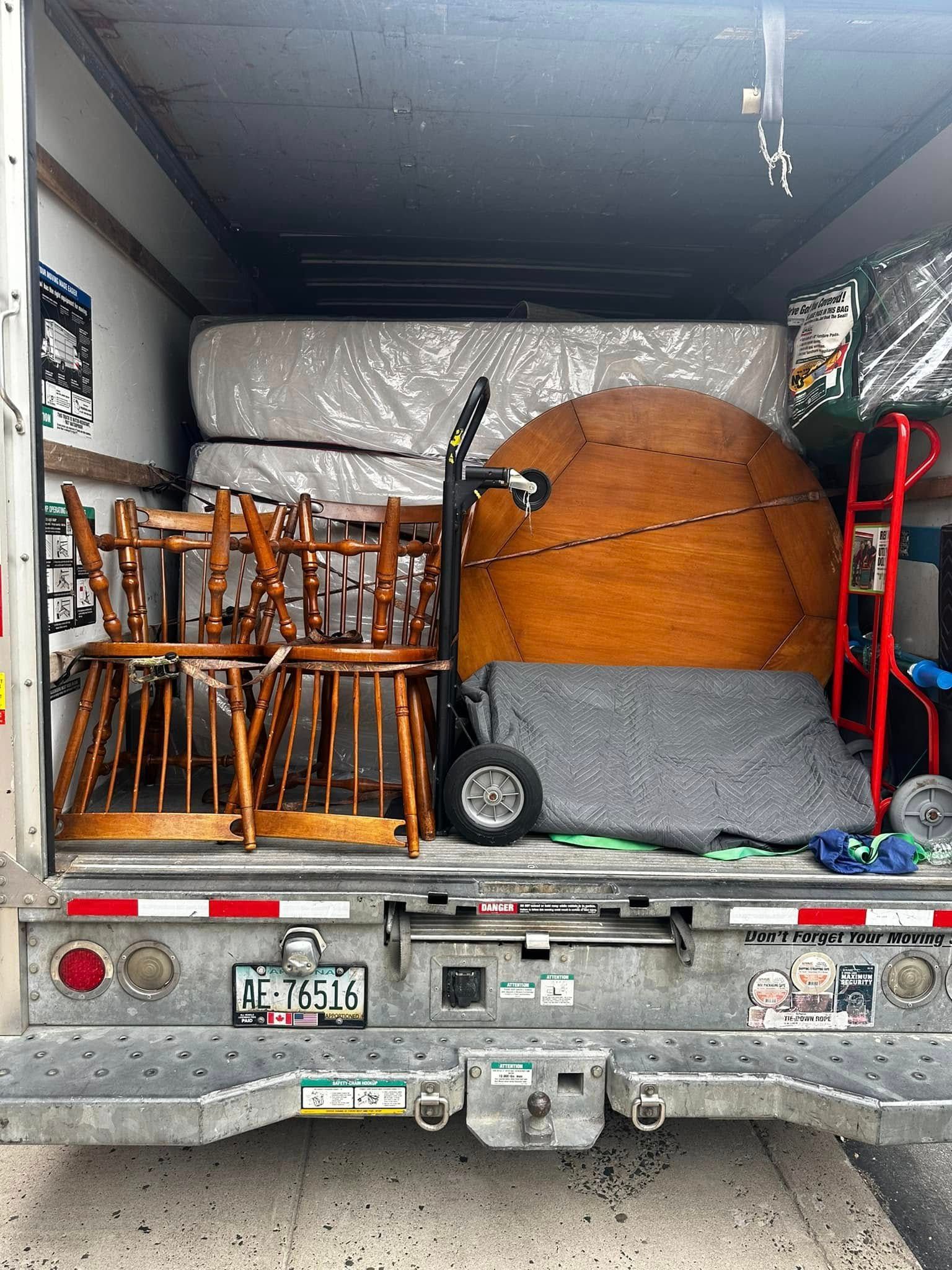 A truck bed loaded with furniture and a mattress for moving.