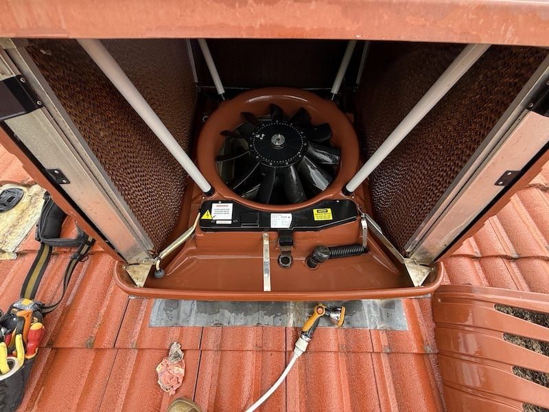 A fan is sitting on top of a tiled roof.