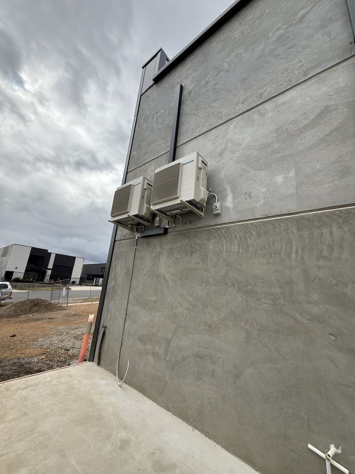 Two air conditioners are mounted on the side of a building.