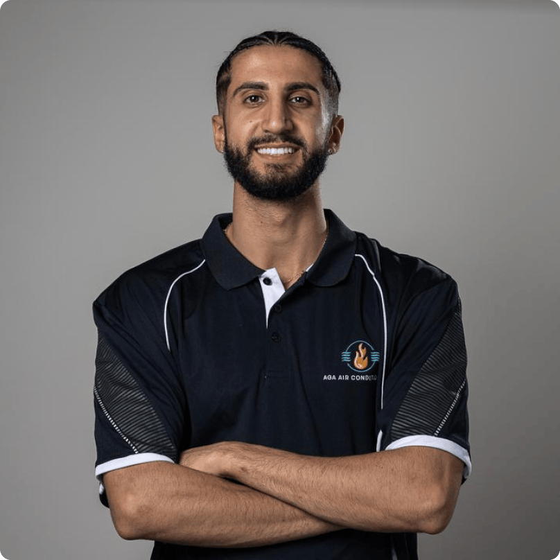 A man with a beard is wearing a black polo shirt with his arms crossed.