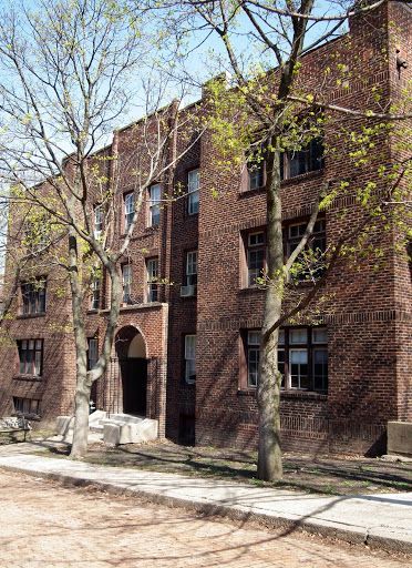 Brick apartment building with trees in front.